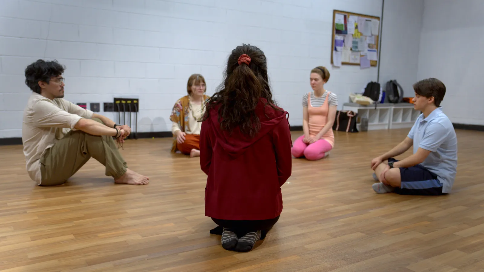 Performing students sit in a circle 