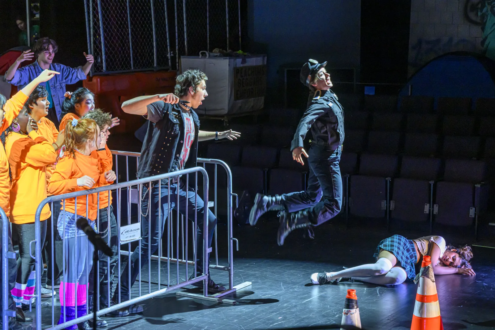 Macheath stands behind bike racks with his knife pulled back while Captain Smith jumps after just having been stabbed in the rear end