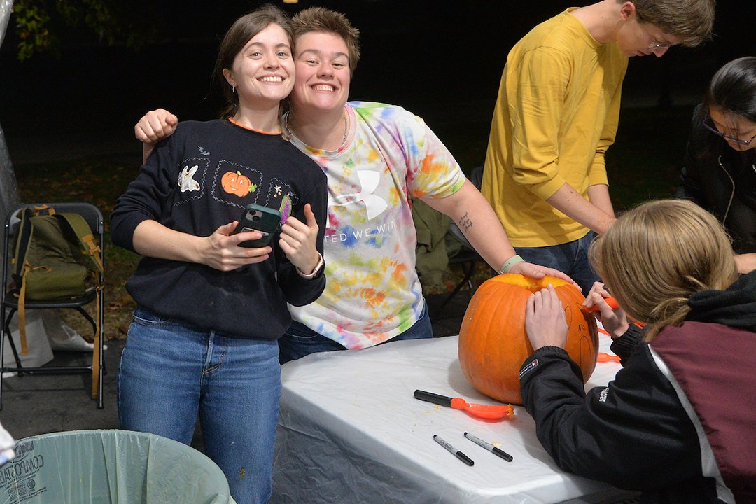 Students carve pumpkins at night