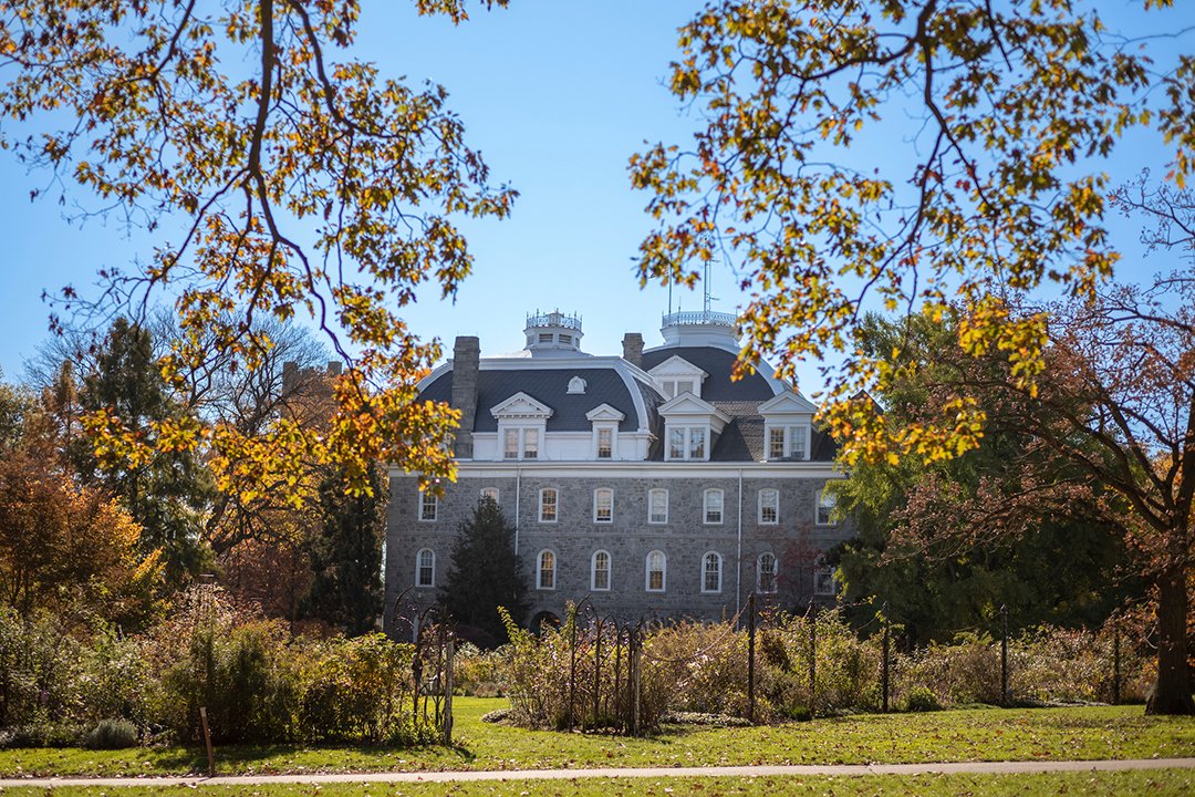 Parrish Hall framed by trees with falling leaves