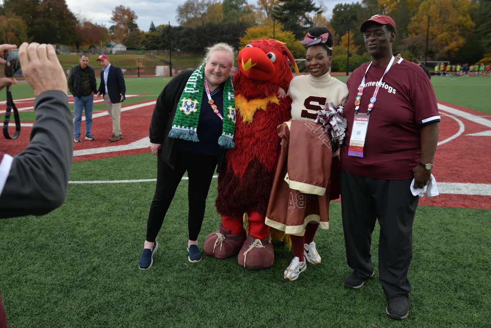 Group of people pose with Phineas the Phoenix standing on turf field