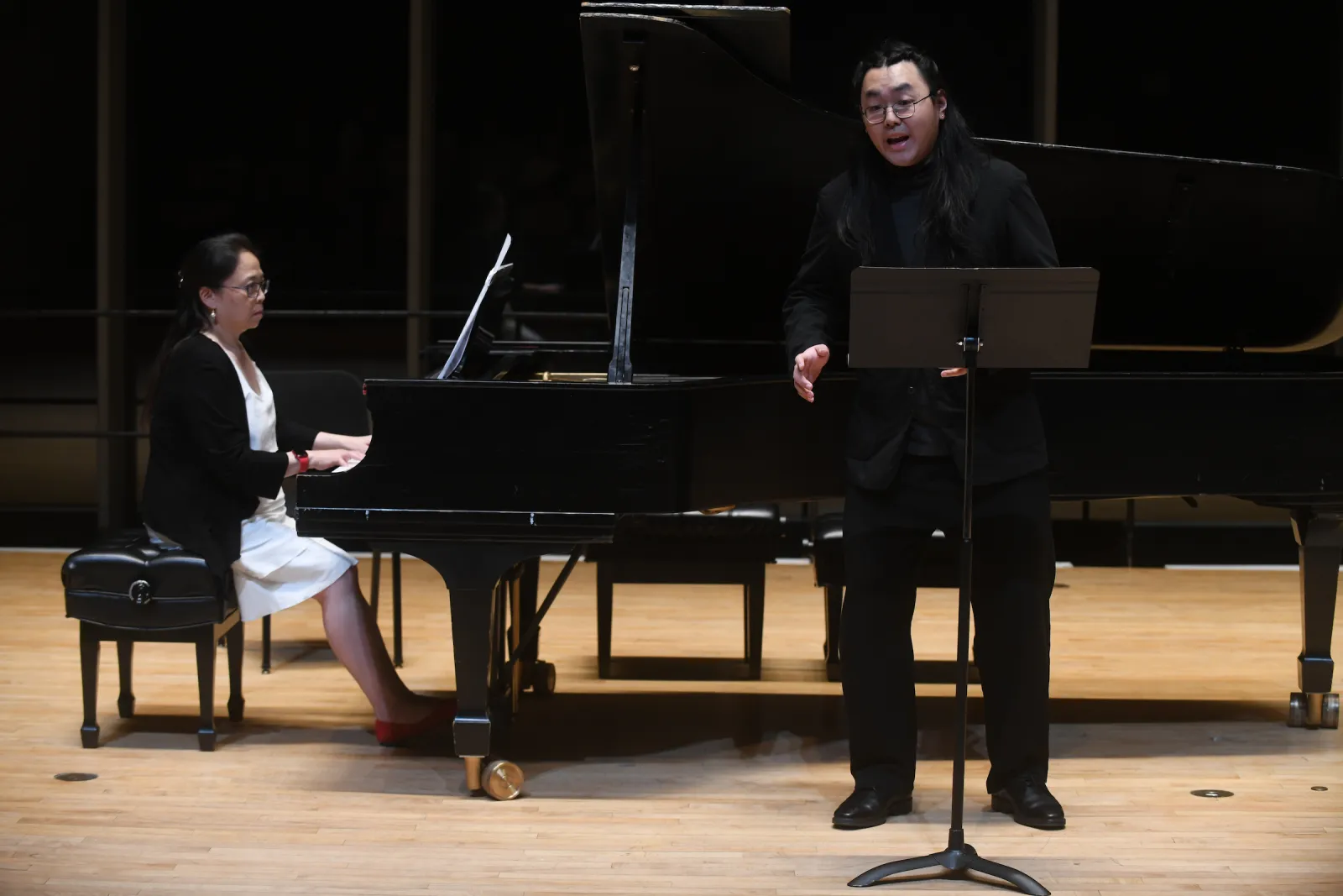 Person sings while standing in front of piano played by accompaniment
