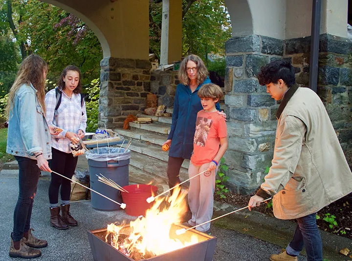 Students and community members make s'mores over a fire