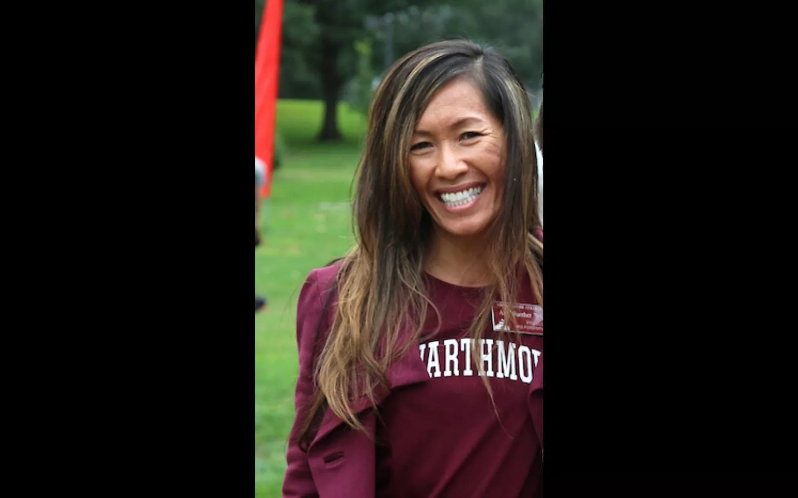 Woman with long brown highlighted hair wearing a Swarthmore garnet tee shirt smiles at the camera