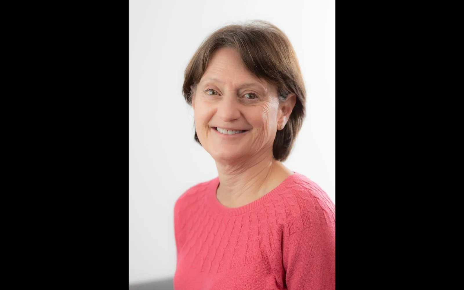Head shot of a woman with short brown hair wearing a pink shirt.