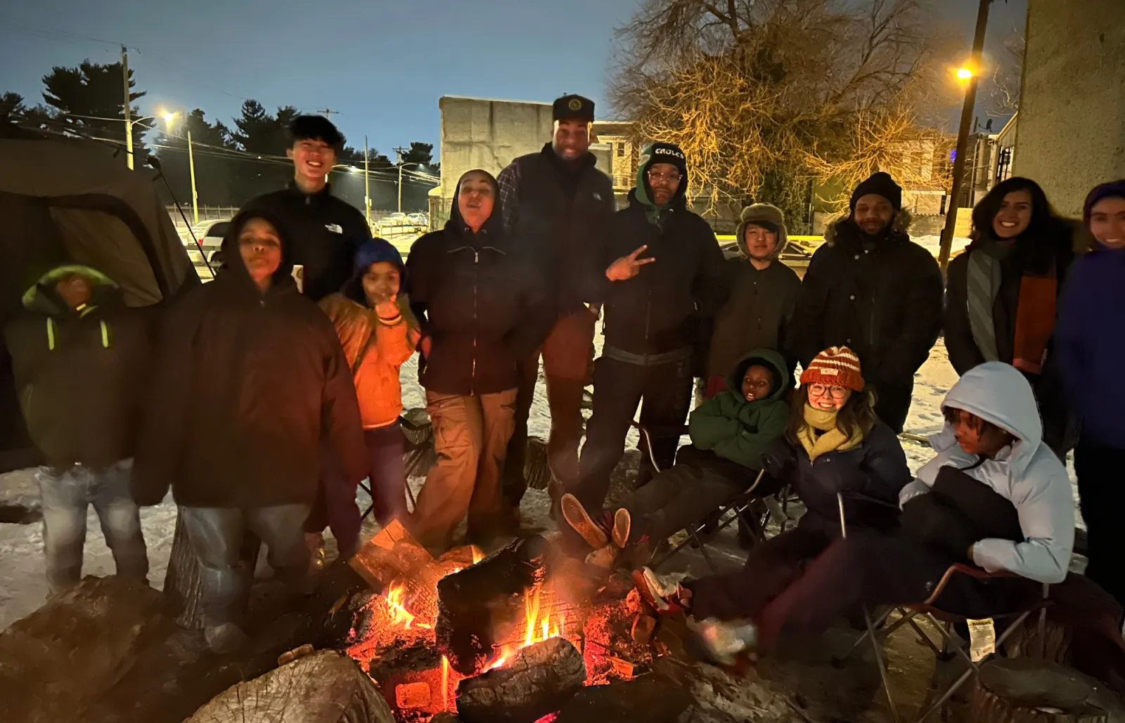 People gathered around a fire outside in the snow