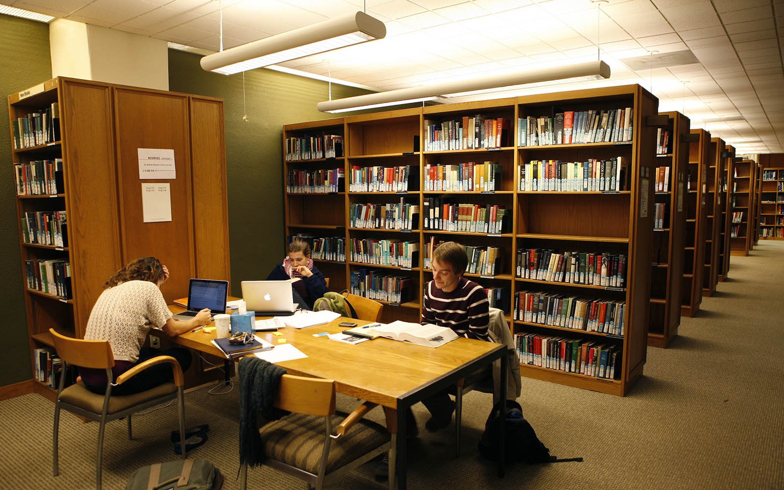 students at a table near book shelves