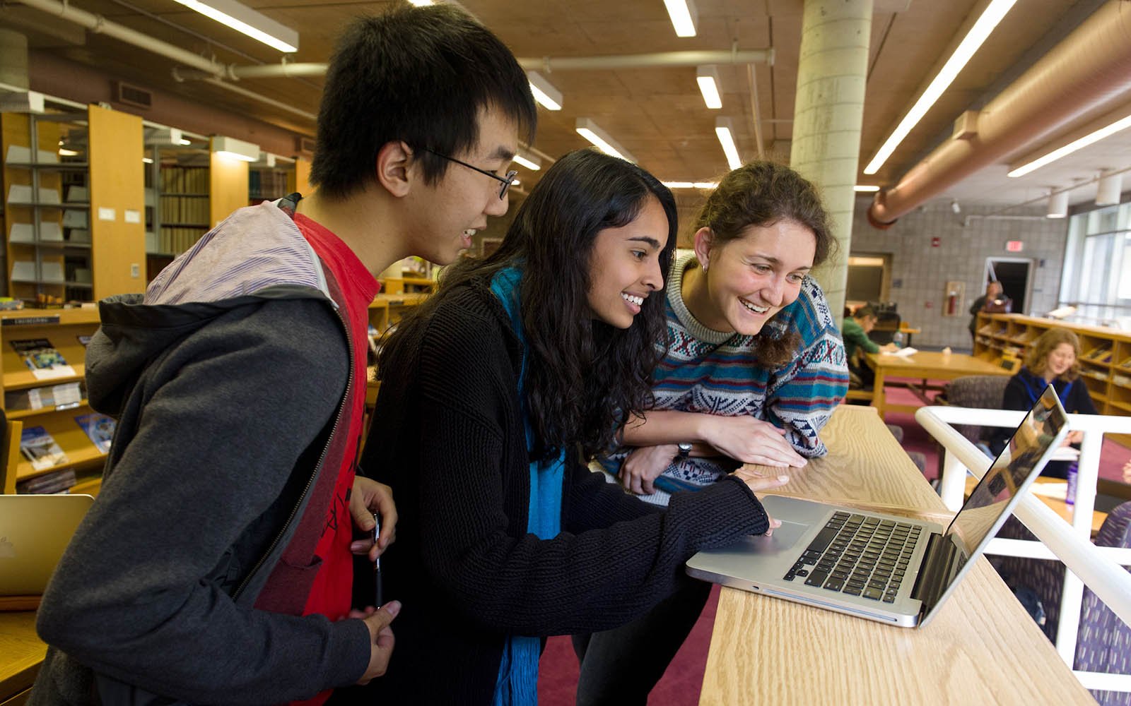 three students looking at a laptop