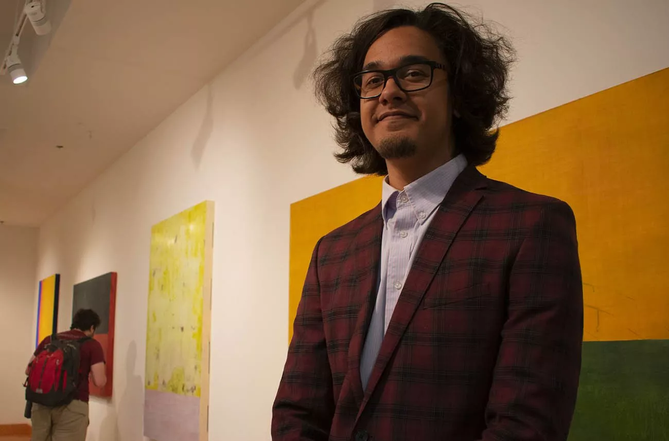 Student stands in front of artwork in List Gallery