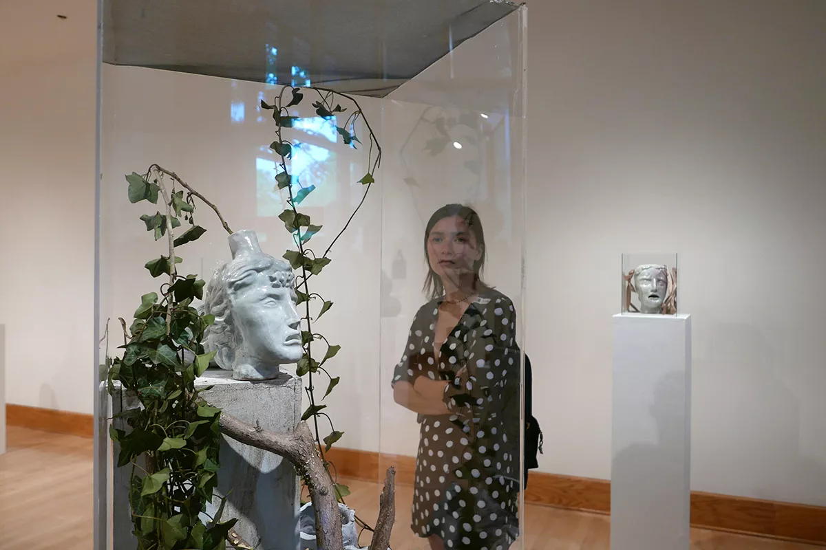 Visitor examines leaves behind glass in List Gallery exhibition