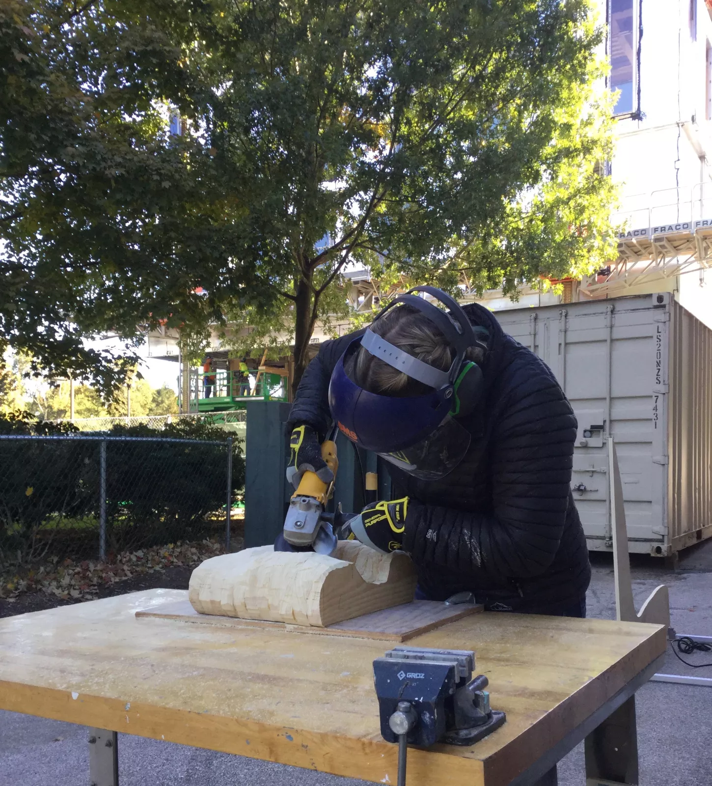 Student sanding sculpture outside