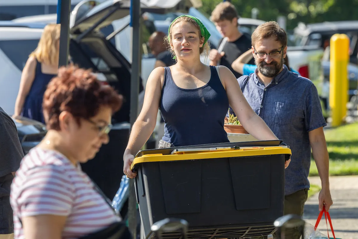 Student carries large crate into dorm during move-in day