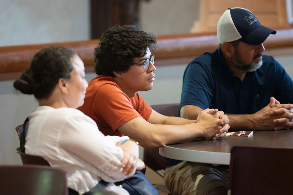 Student sits at table with parents