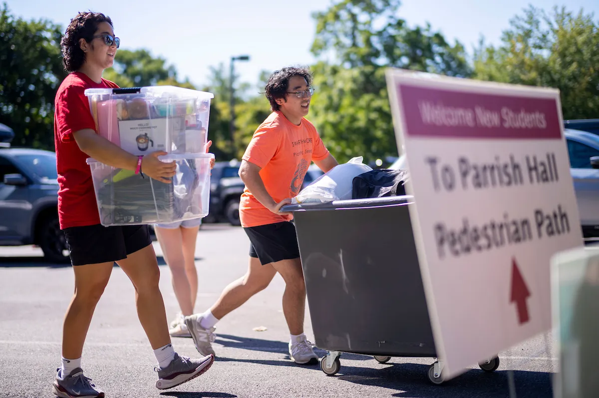 Two students cart and carry items during move-in day