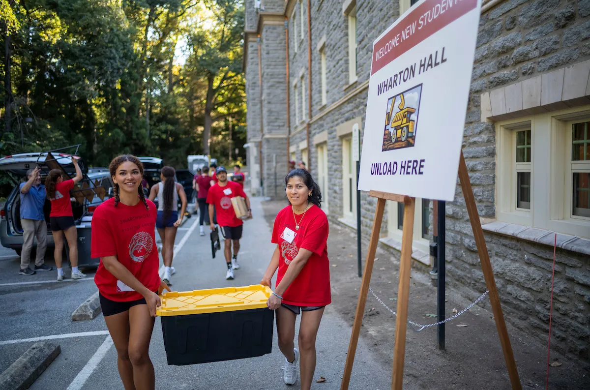 Two orientation team members help carry box during move-in