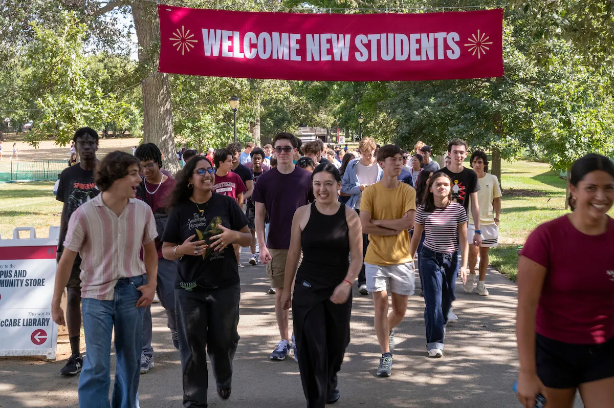 Students walk down Magill Walk with "Welcome New Students" banner in background