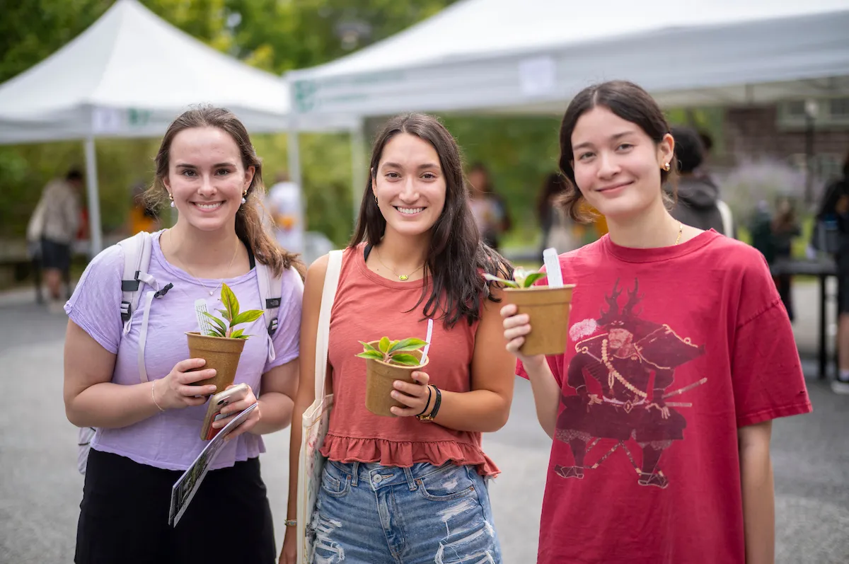 Students pose with potted plants at plant giveaway
