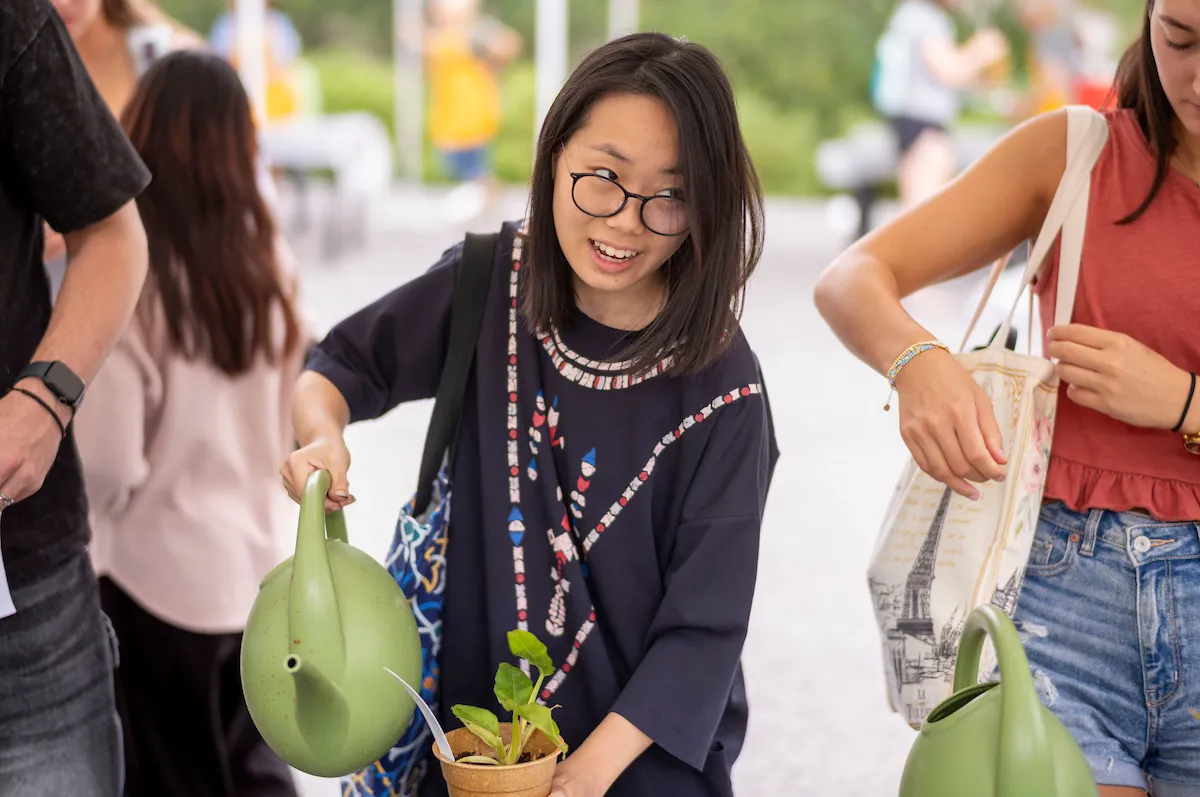 Student waters plant at plant giveaway