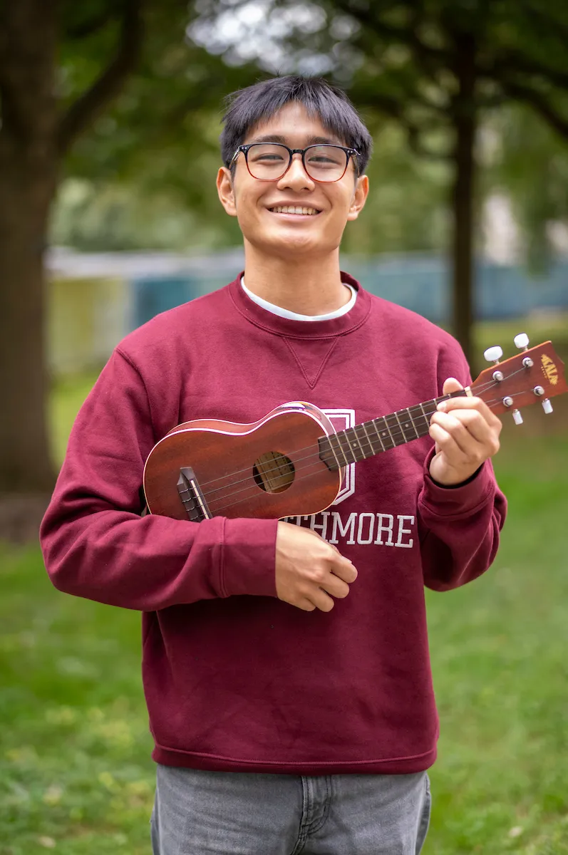 Student with Swarthmore sweatshirt holds ukulele 