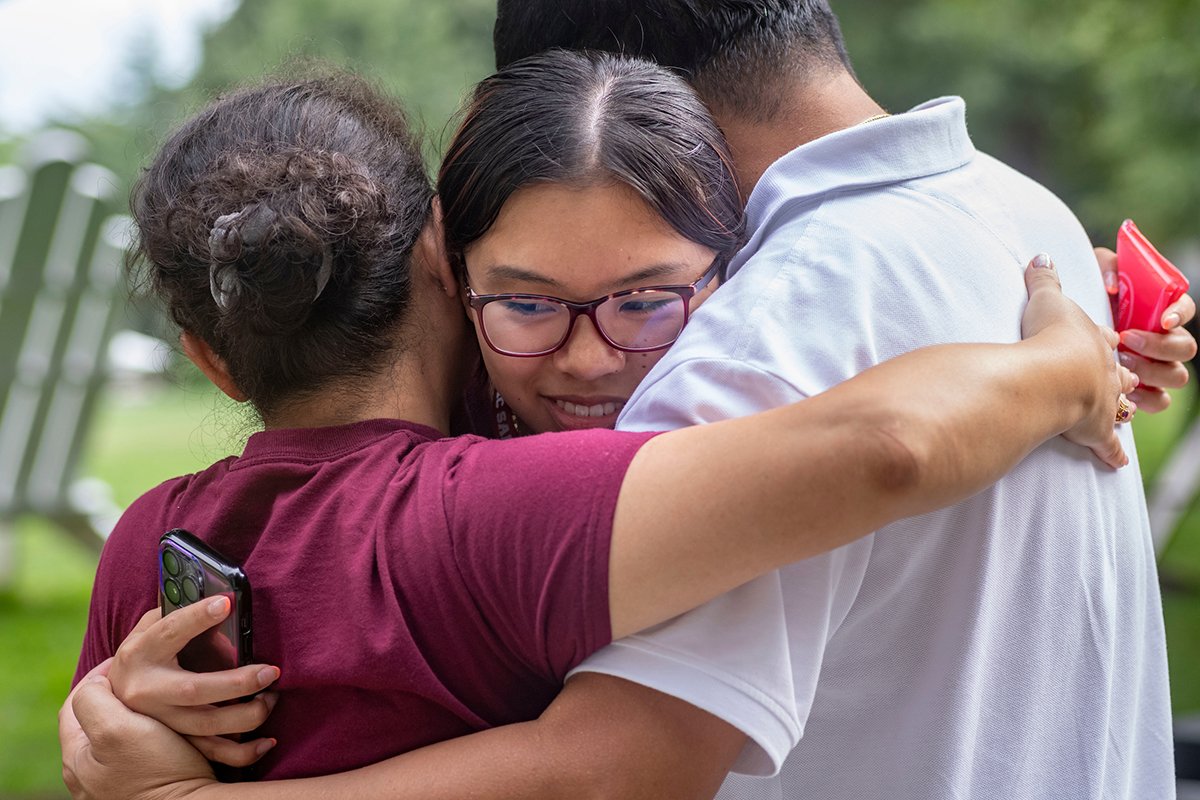 Student receives group hug from parents