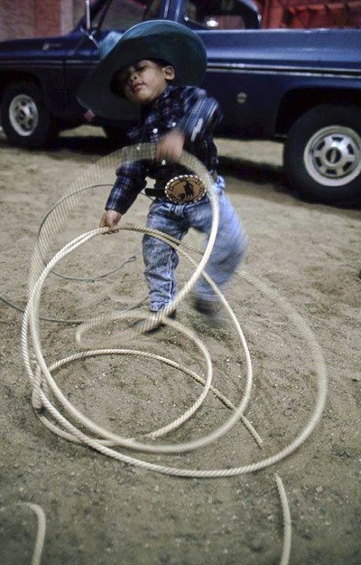 A four-year-old plays with his fathers rope during a rodeo in Dallas.