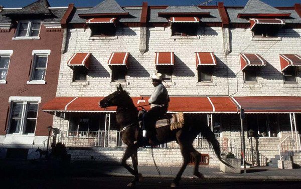 Bob Hill rides his horse down a street of rowhomes in North Philadelphia