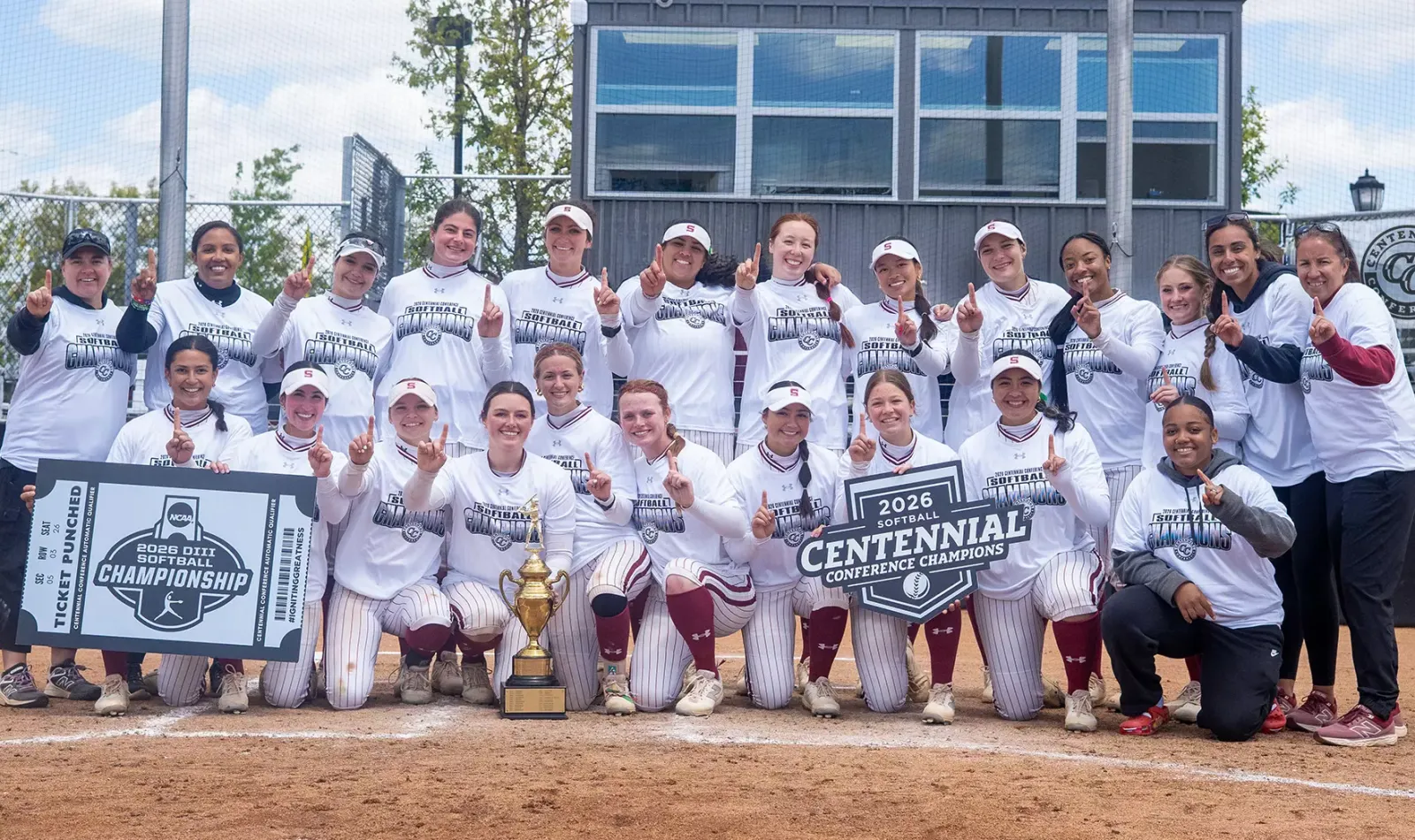 Softball team on field with trophy after winning conference title