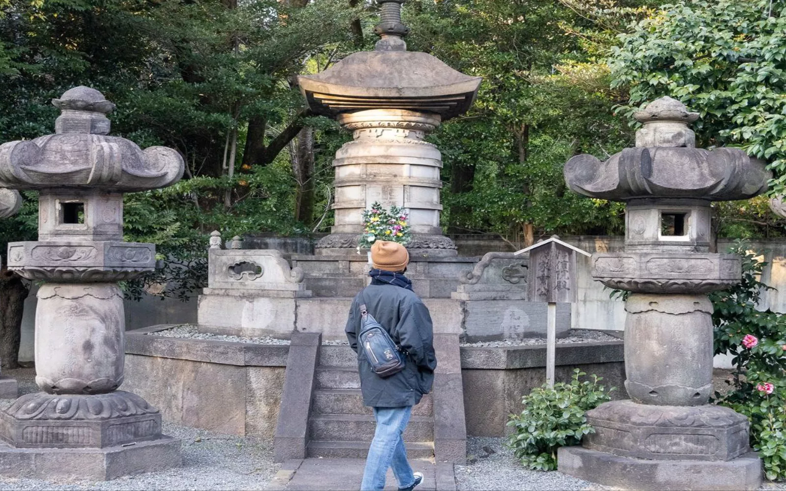 Student walking past stone sculptures and trees