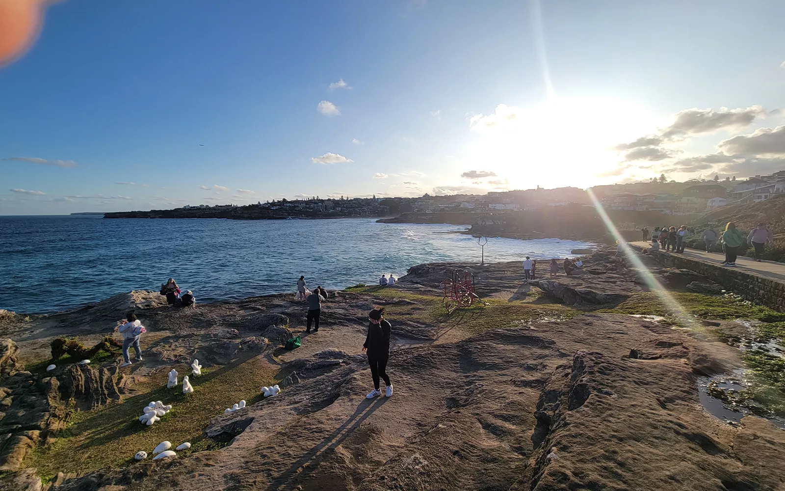 People wandering around rocks on beach (viewed from higher vantage point)