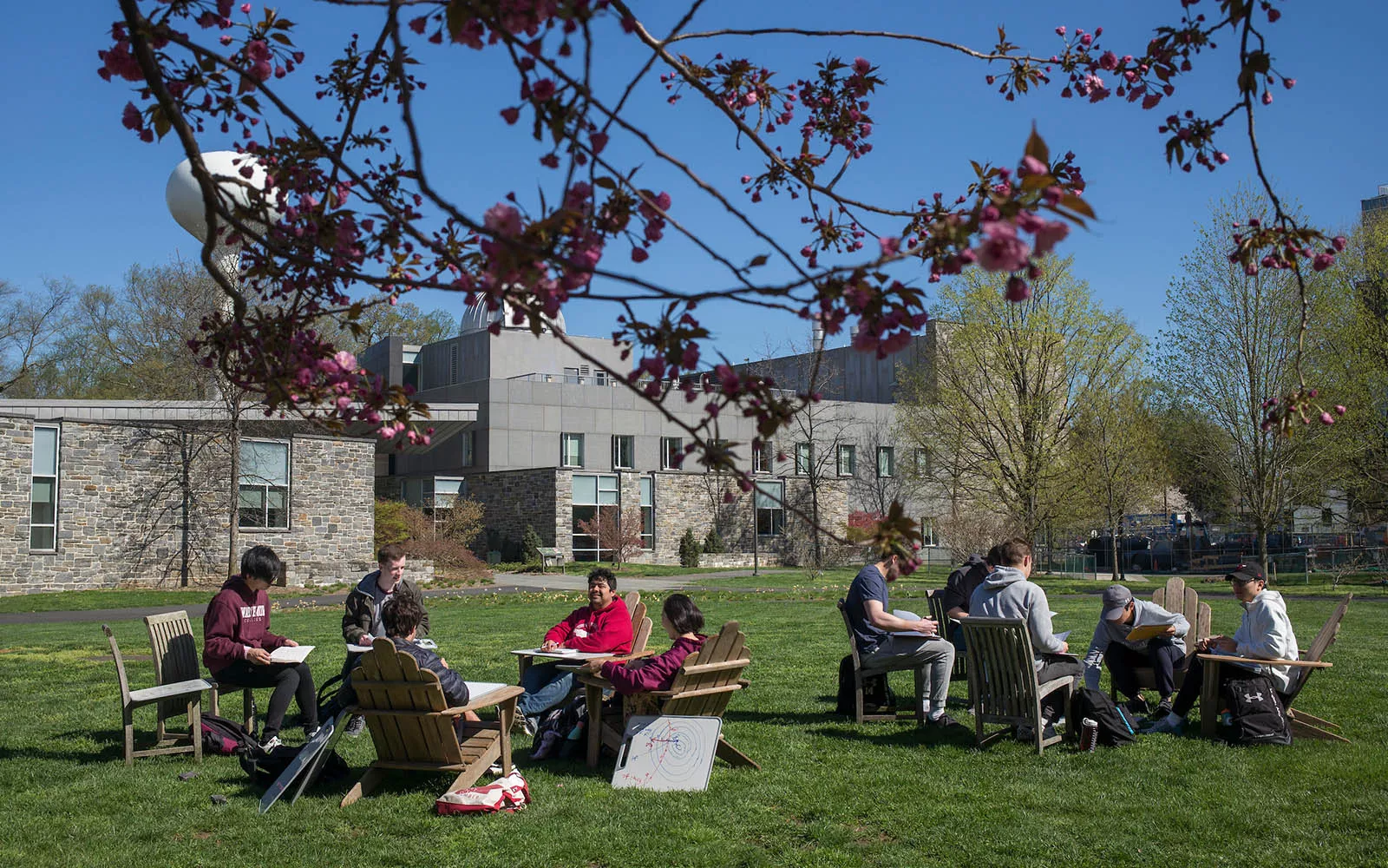 two groups of students sitting outside in chairs 