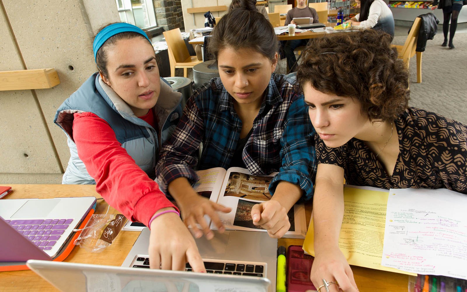 Three students looking at a laptop