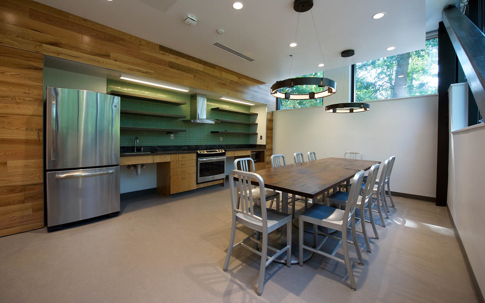 Kitchen space with table in the middle of the room and large metal fridge to the left.
