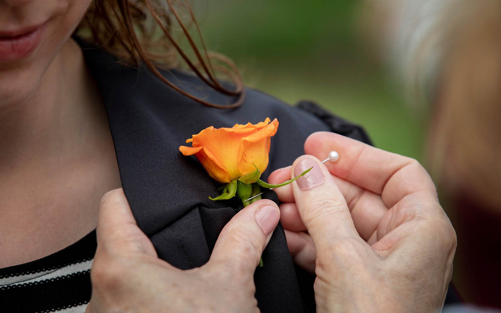 student getting rose attached to gown