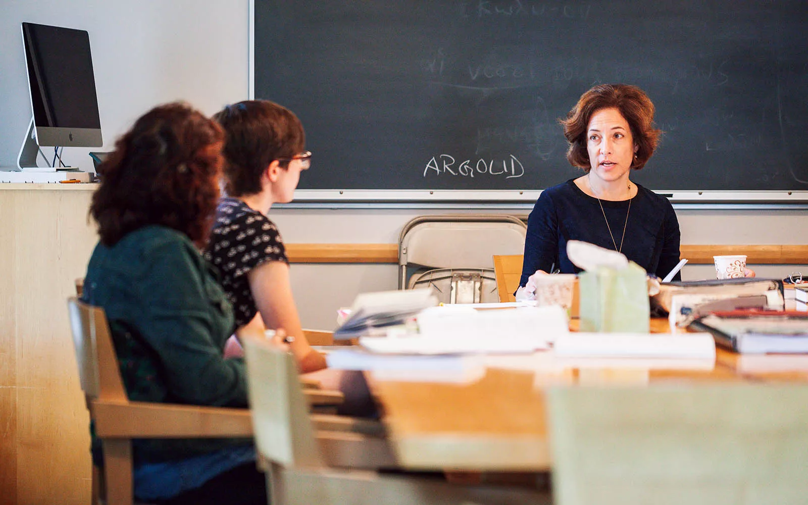 two students and professor at a table