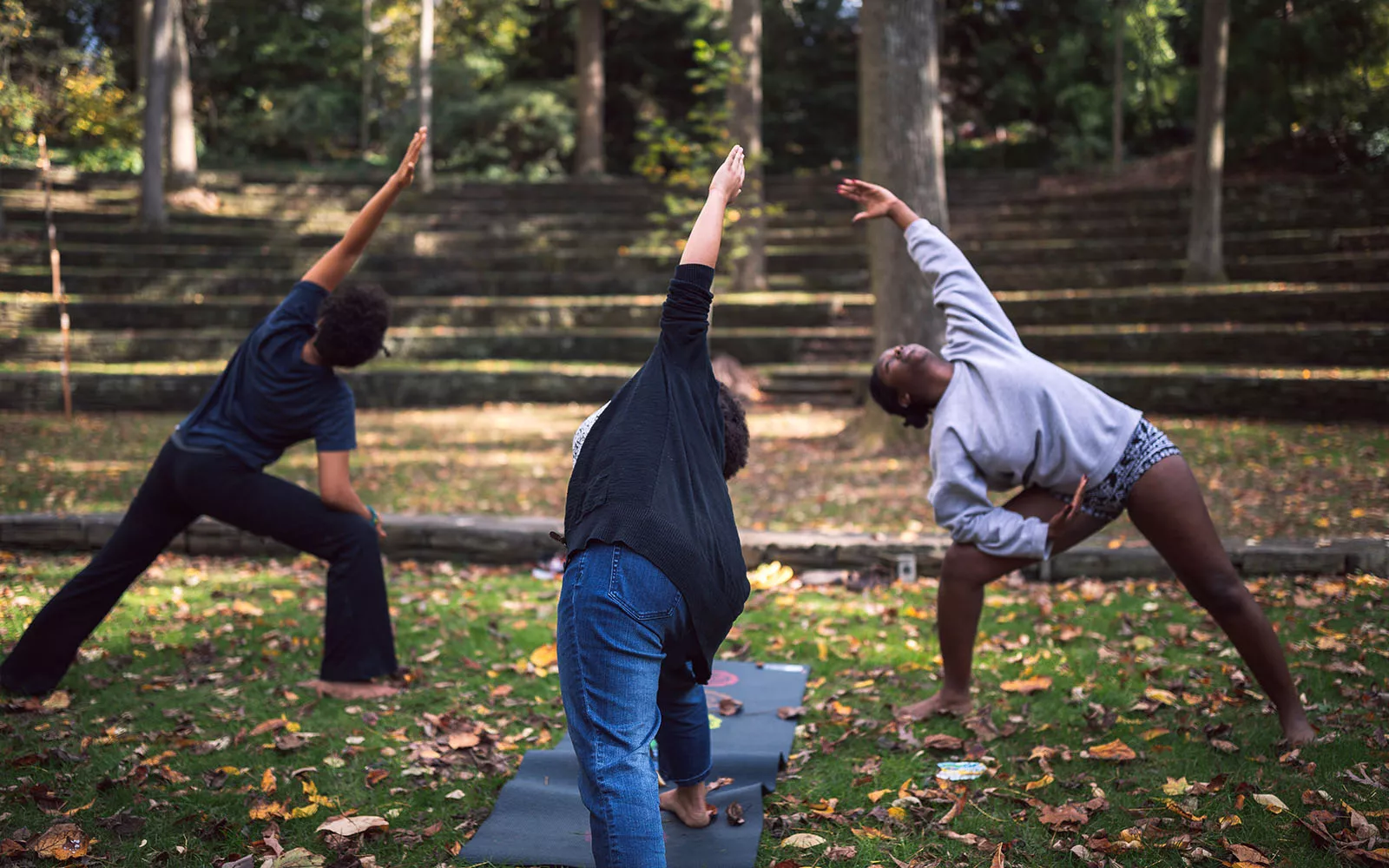 3 women practicing yoga in the amphitheater