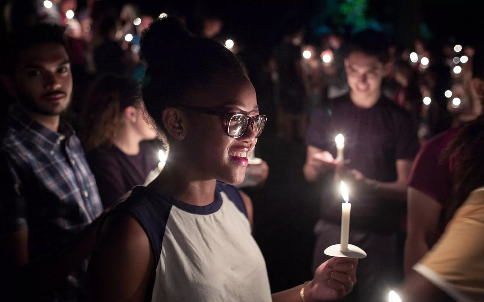 Student holding candle and smiling