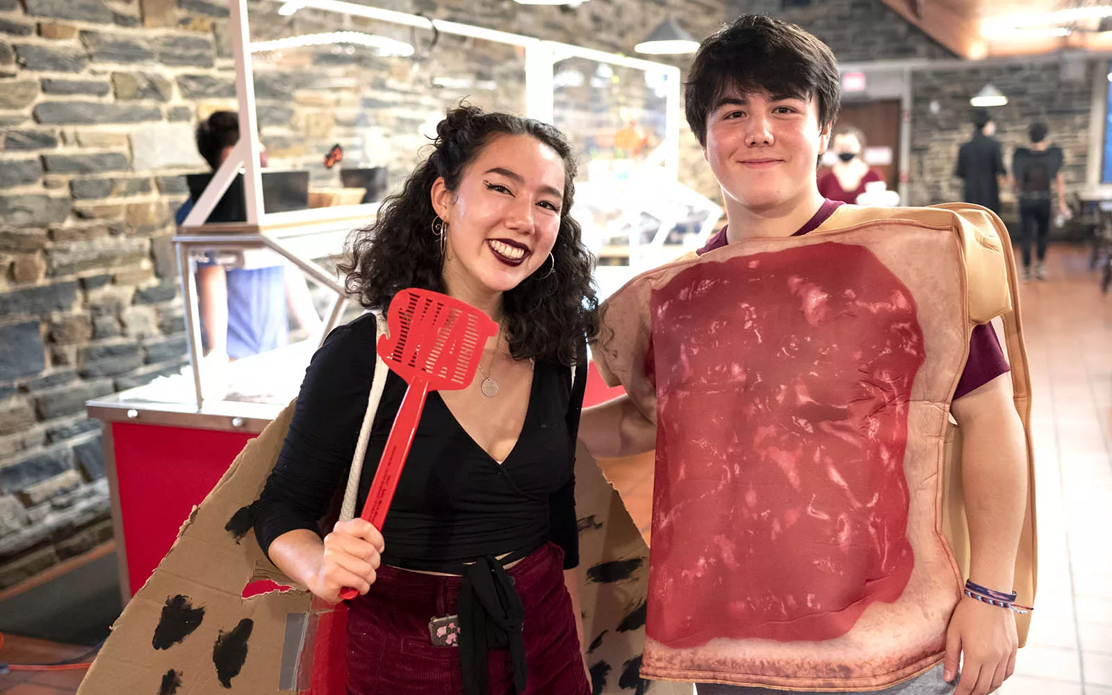 Two students posing in dining hall, one dressed as a sandwich