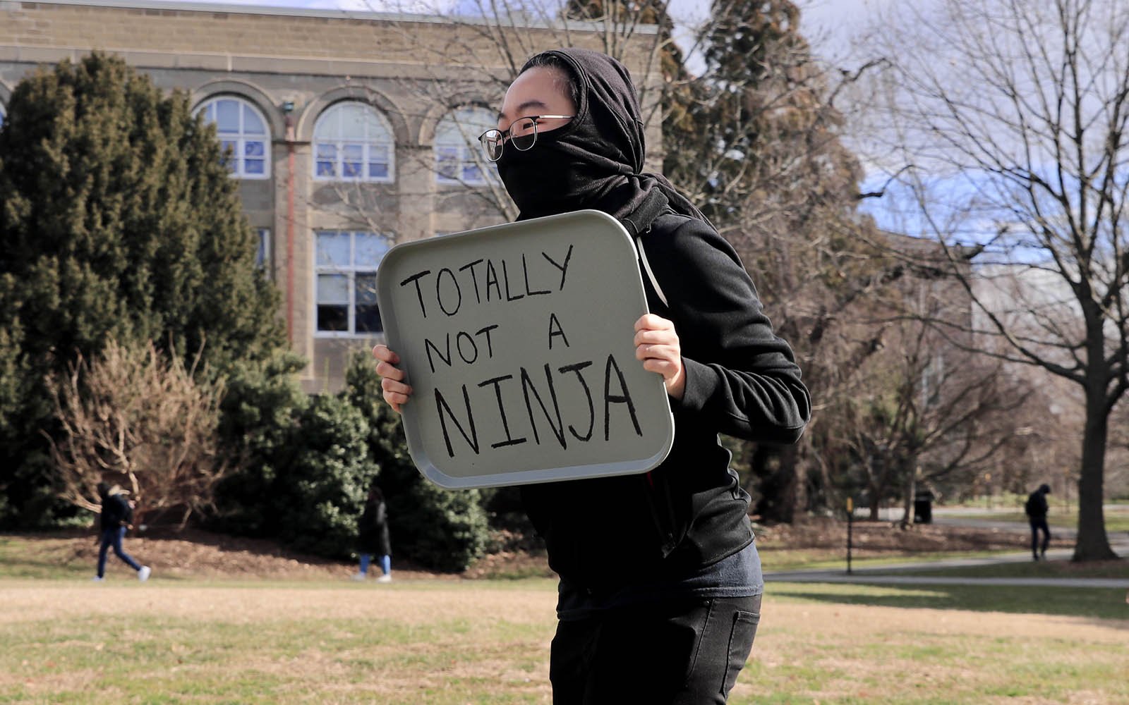 Student dressed as a ninja holding a sign