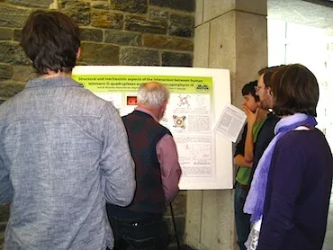 Faculty, students, and visitors gather around Jack Nicoludis and Steven Barrett's poster.