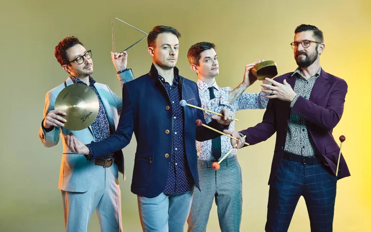 Group of four men hold percussion instruments in group photo