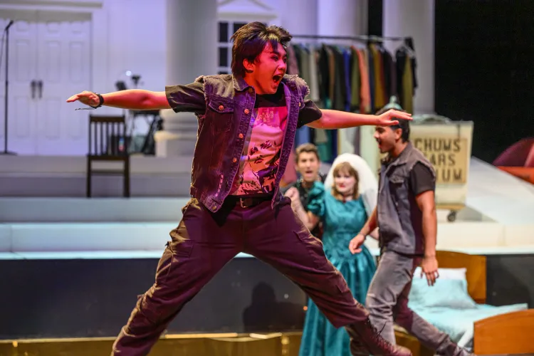 A performer jumps into the air wearing a jean vest and a graphic t-shirt