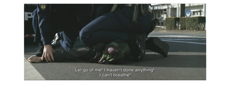 Still from "Final Episode" of a kaijin being detained by the police. A police officer kneels on the kaijin's neck while the kaijin exclaims, "Let go of me! I haven't done anything! I can't breathe!"