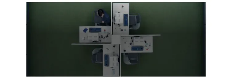 Still from Severance S1 E5: “The Grim Barbarity of Optics and Design” showing a birds eye view of four desks at Lumon and an employee at one of the desks.