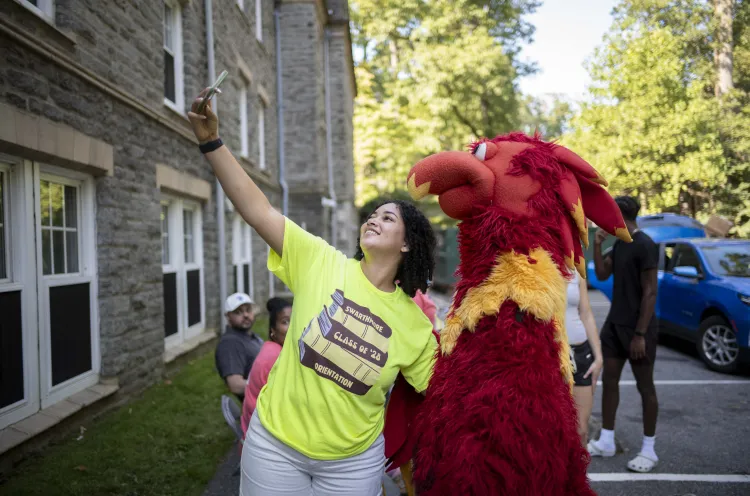 A picture of Area Coordinator Desire Foreman taking a Selfie with the Phineas the Phoenix mascot.