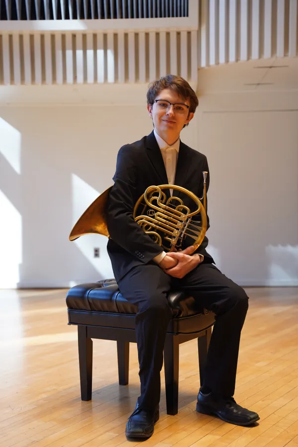 Duncan Wall '26 seated on the Lang Concert Hall stage with his french horn