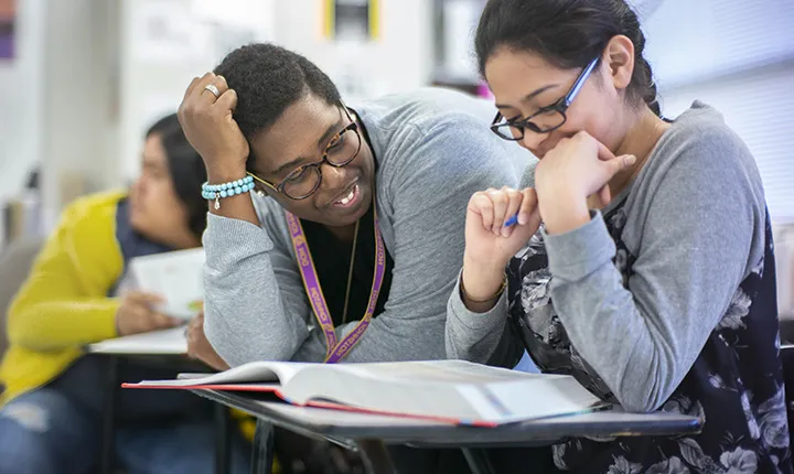 Kimberly St. Julian-Varnon '12 sitting with student in classrooom