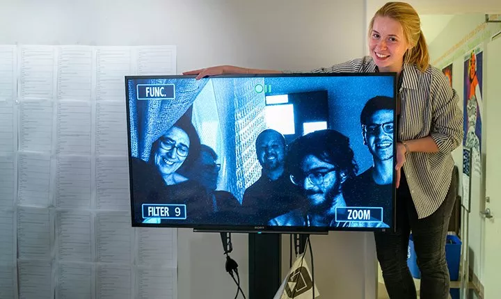 Student poses with TV monitor in exhibit