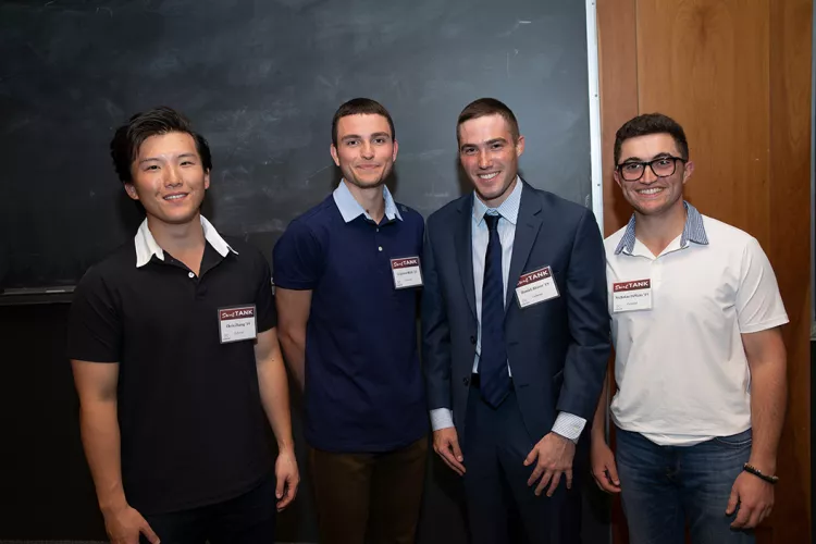 Four male students stand in front of chalkboard