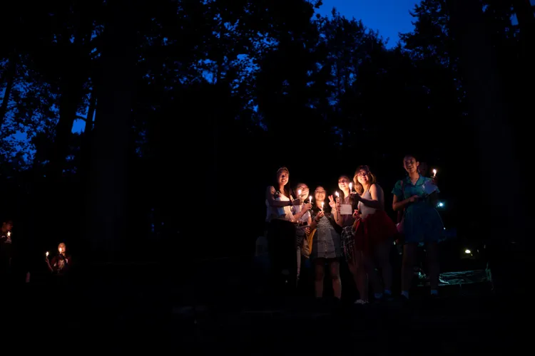 Students hold candles in amphitheater during First Collection