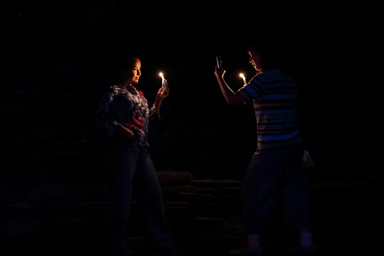 Person holds candle and poses for picture while another student uses phone